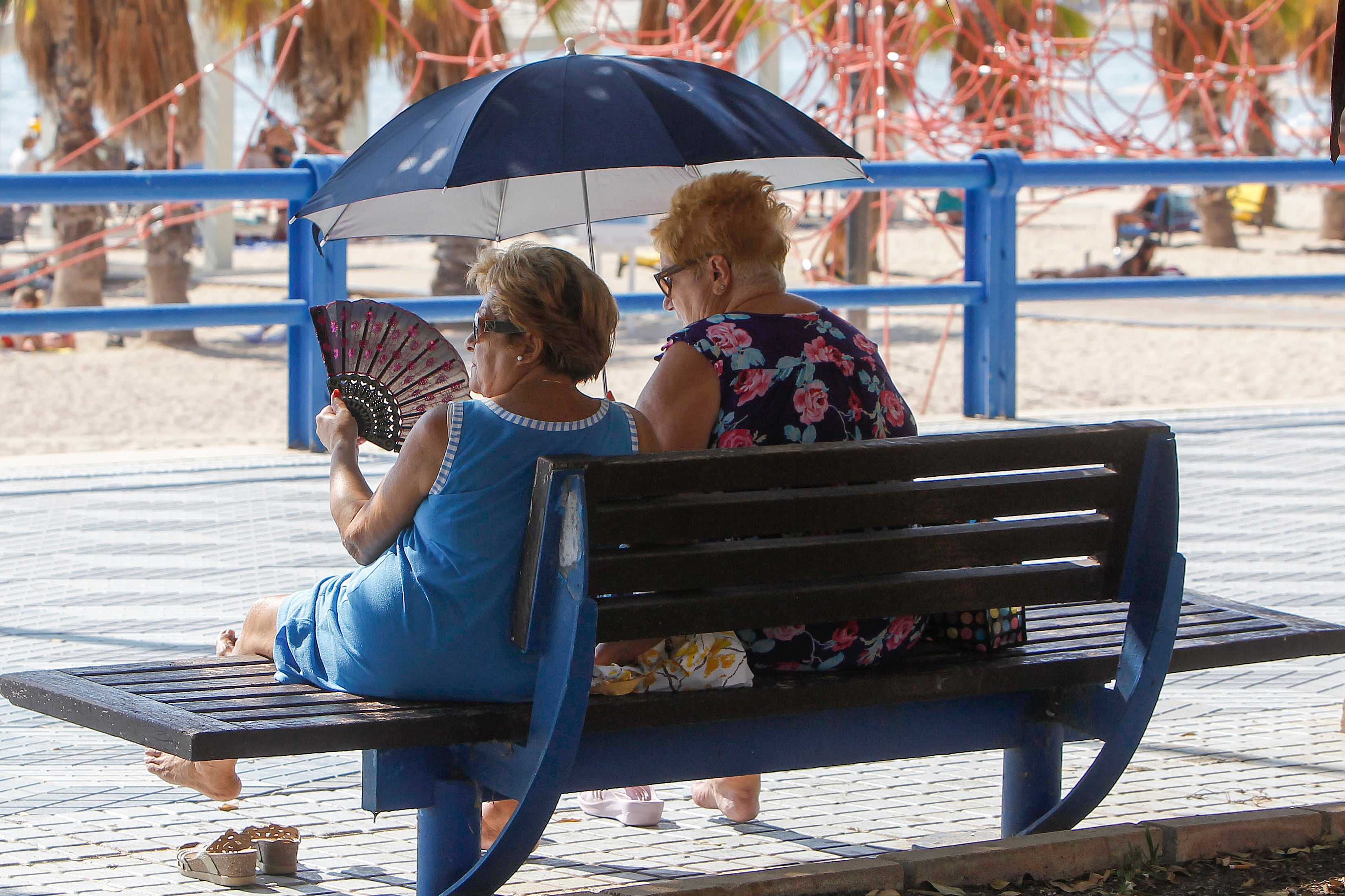 Dos mujeres se protegen del sol y de calor con abanico y parasol en el que se viven altas temperaturas en este inicio de otoño.