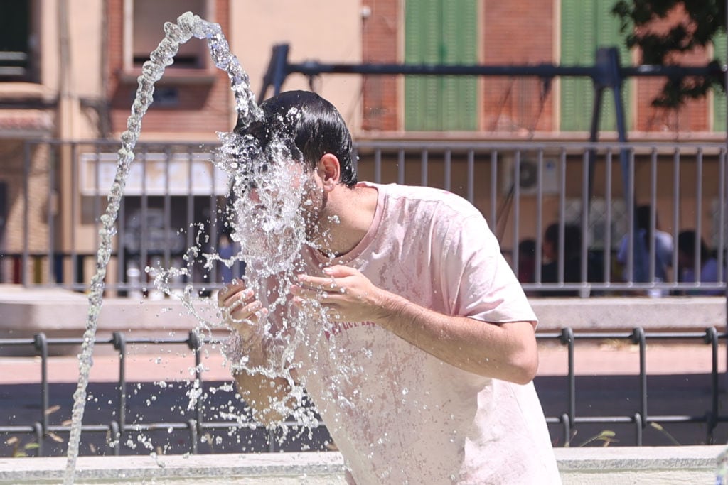 Una persona se refresca en una fuente durante la ola de calor.