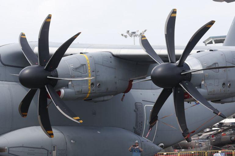 A man (bottom-C) is dwarft while taking photographs underneath the wing and propeller engines of Royal Malaysian Air Force (RMAF) Airbus A400 transport plane at the static display ahead of the Singapore Airshow at the Changi Exhibition Centre in Singapore