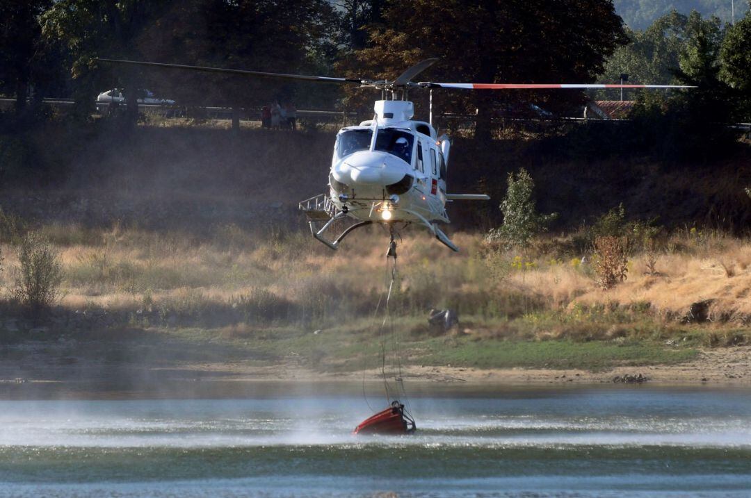 Un helicóptero recoge agua del pantano de El Pontón para combatir el incendio forestal declarado cerca del Real Sitio de San Ildefonso-La Granja, en la frontera del Parque Nacional de Guadarrama