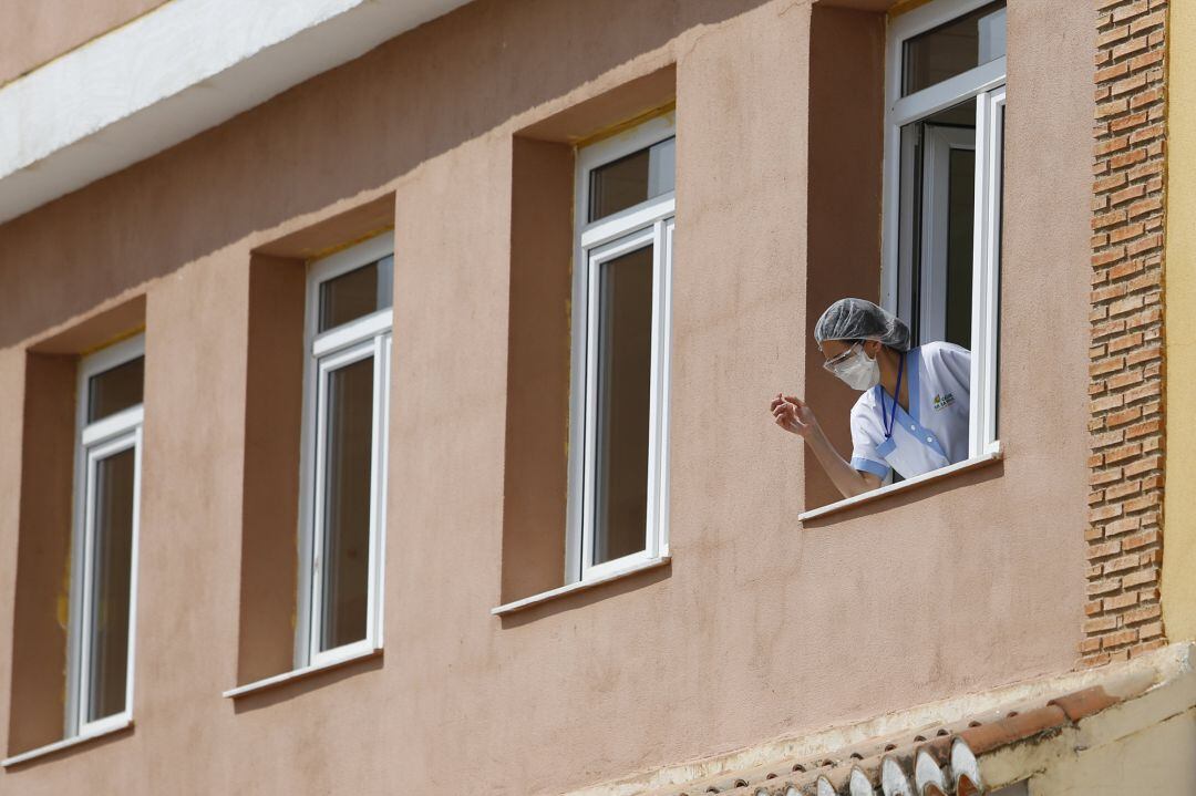 Una trabajadora se asoma a una ventana de  el centro de mayores  
 