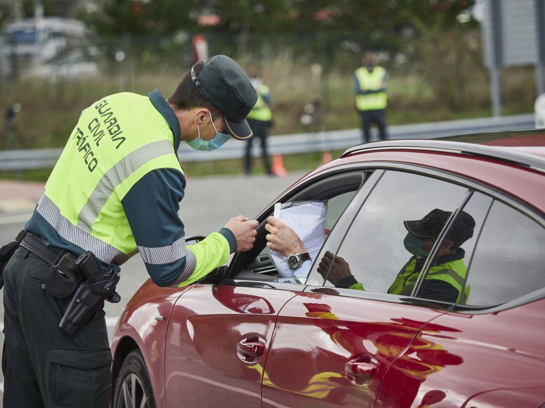 Un agente de la Guardia Civil de Tráfico comprueba la documentación de un conductor en un control policial en la frontera entre Navarra y Álava
