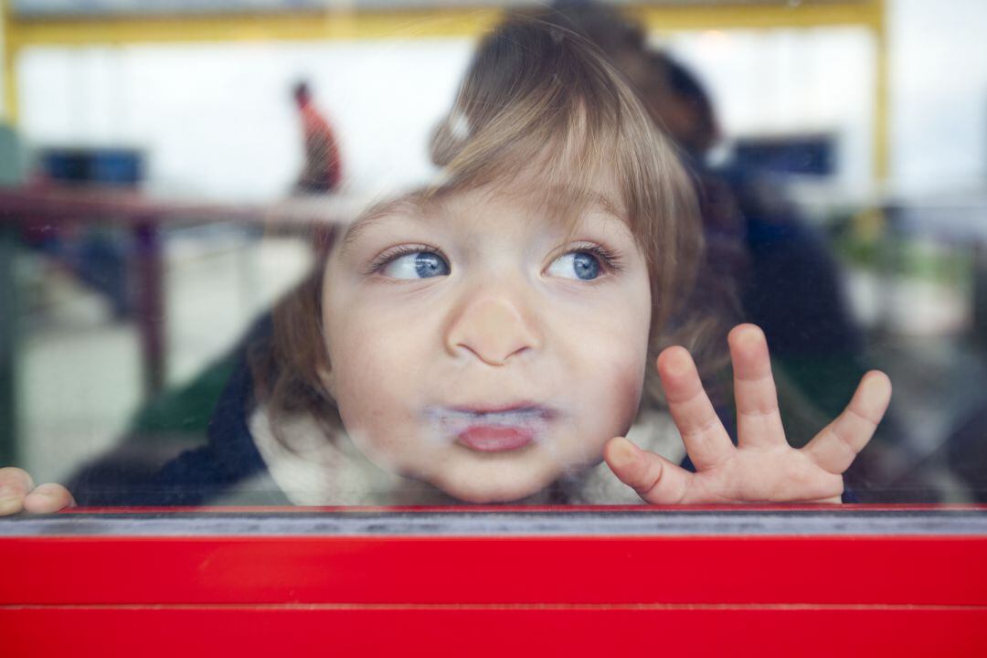 Un niño pegado a un cristal. 