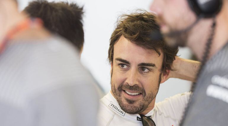 Fernando Alonso conversa con un miembro de su equipo en el box de McLaren