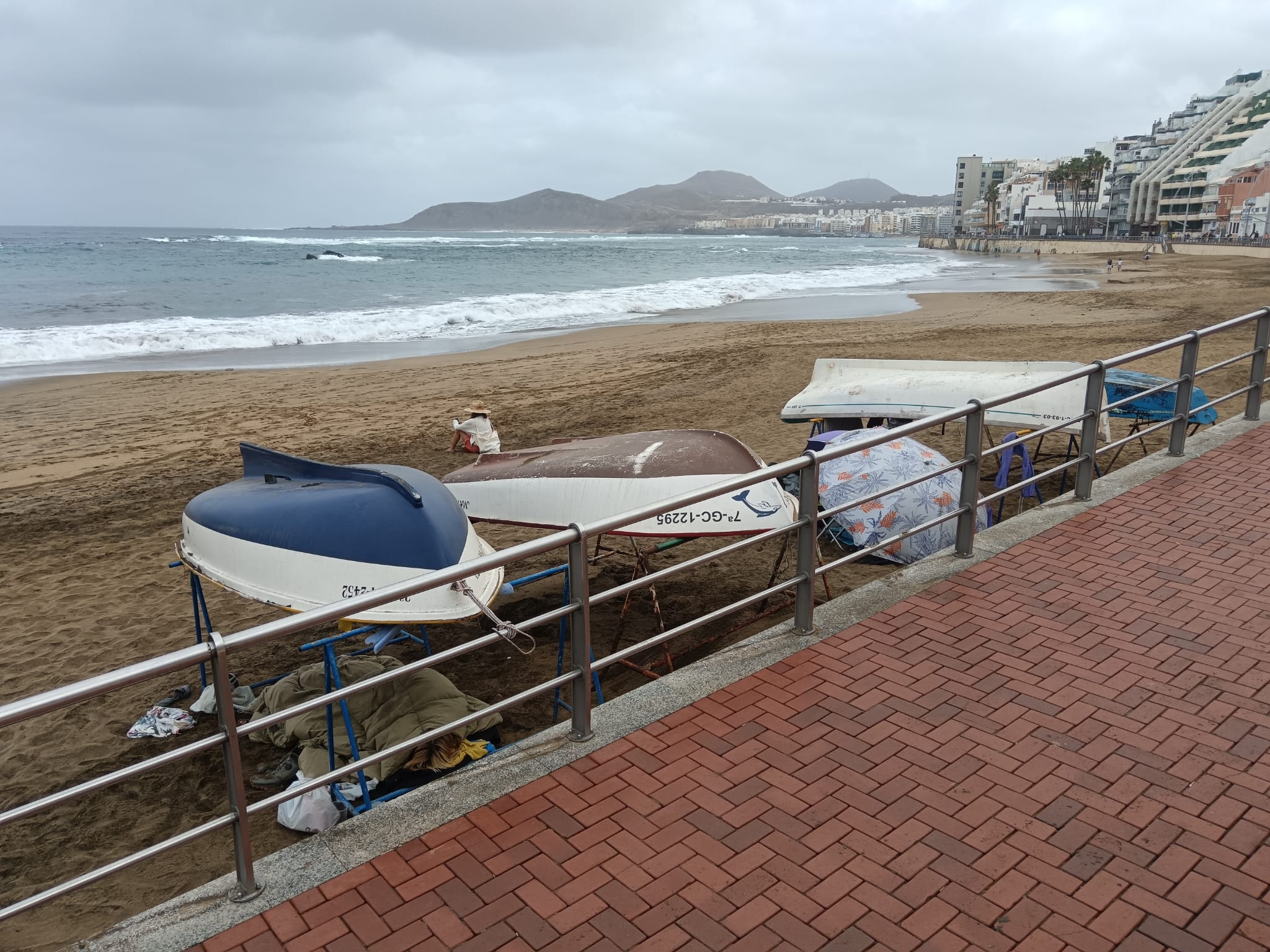 Una pareja pernocta bajo las barquillas de la playa de Las Canteras