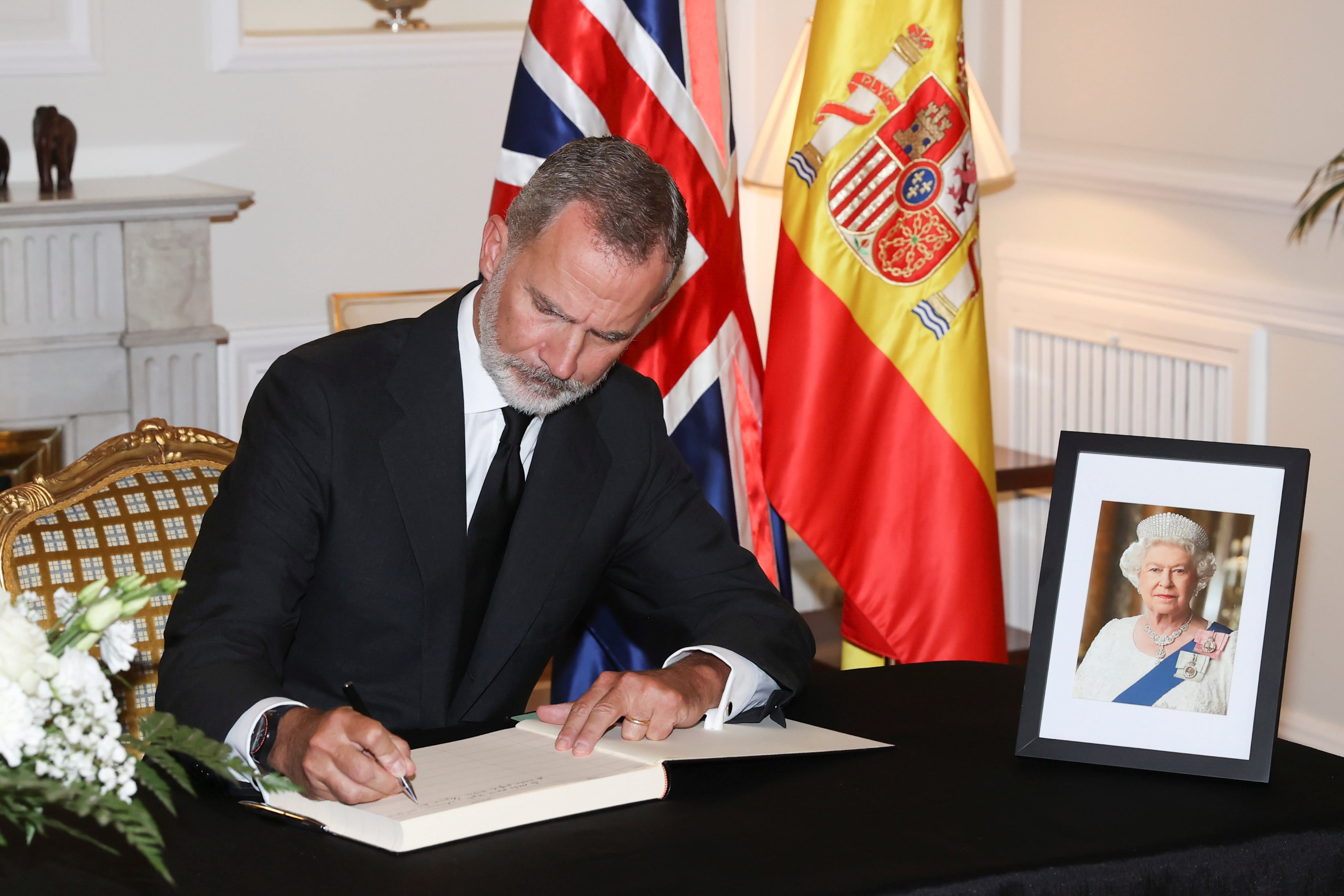 El rey Felipe VI firma en el libro de condolencias por el fallecimiento de la reina Isabel II, durante la visita de los monarcas españoles a la residencia del embajador del Reino Unido en España, Hugh Elliott