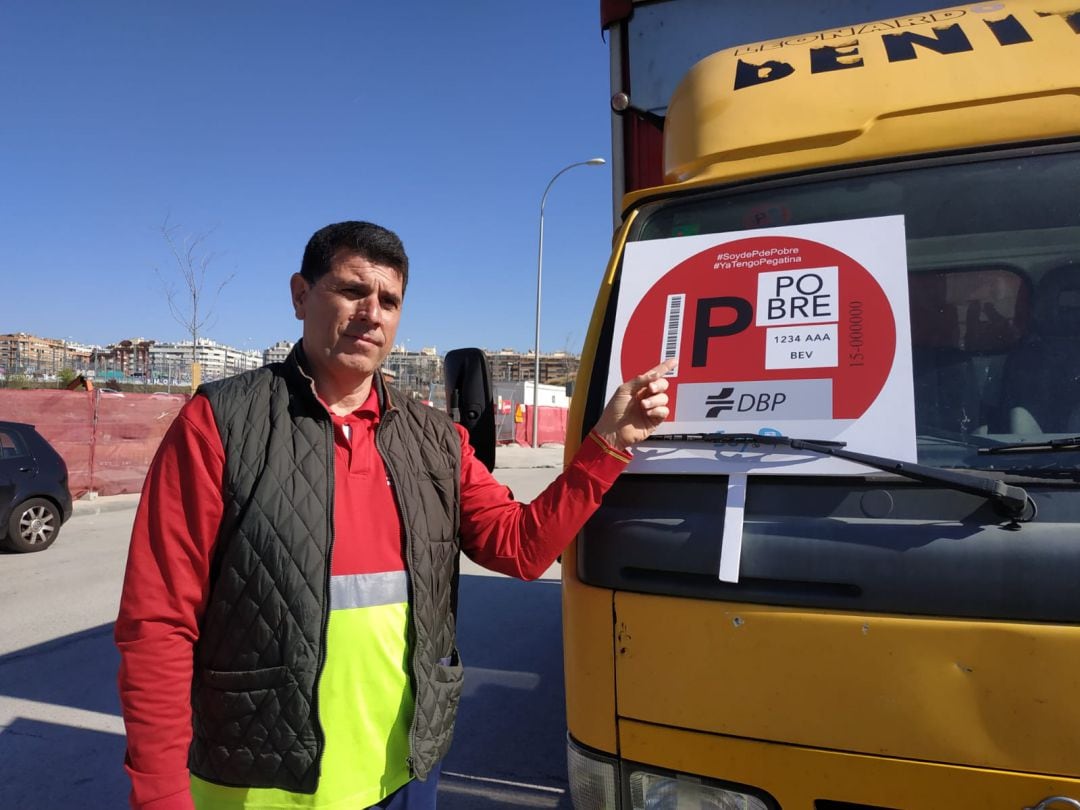 Javier Benito, de la Asociación de Transportistas de Madrid, junto con un cartel que representa las pegatinas de la campaña. 