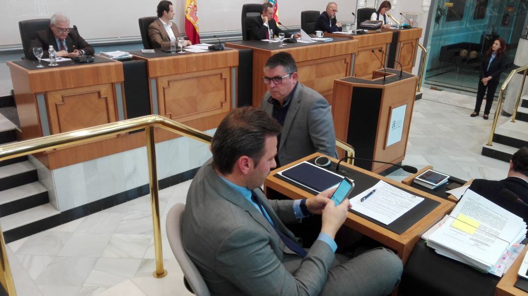 Alejandro Morant tecleando en su móvil, bajo la mirada del diputado de Compromís, Luis Pastor, durante un pleno de la Diputación.