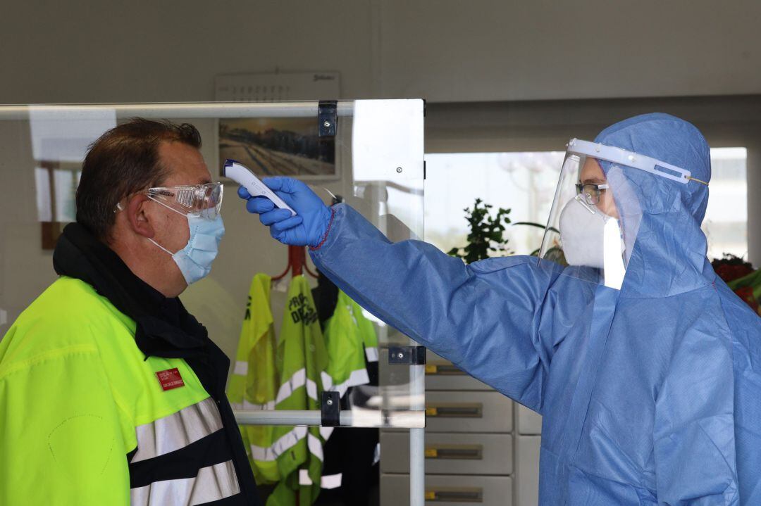 Un sanitario toma la temperatura a un trabajador antes de su jornada laboral en la planta de Opel-PSA de Figueruelas tras la presentación del director de Recursos Humanos de la planta, Carlos Iglesias, y la responsable de Prevención y Salud Laboral, Marta Laborda, del protocolo de medidas implantadas en la factoría que permiten volver al trabajo en condiciones seguras frente al coronavirus, en Figueruelas