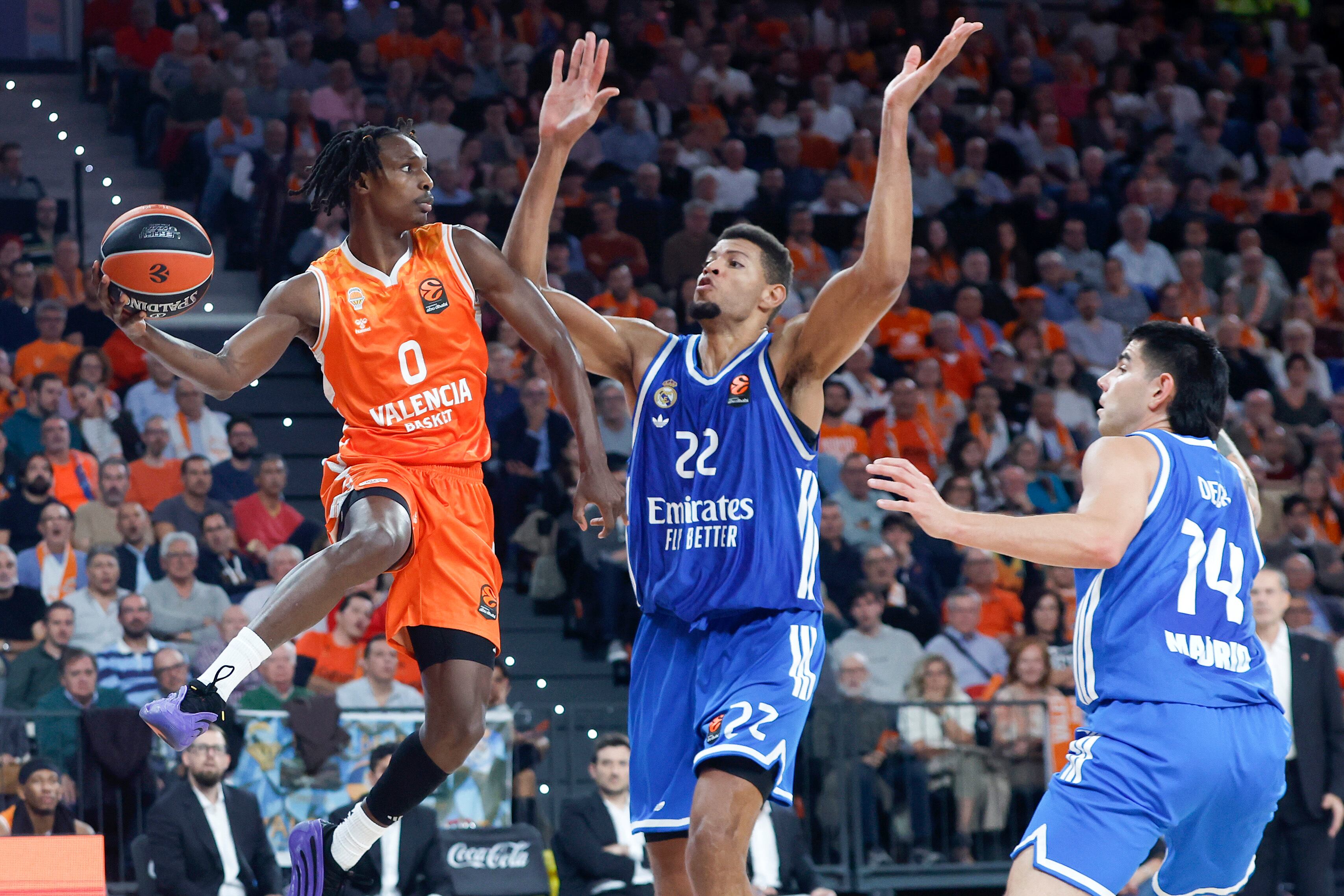 VALENCIA, 11/11/2025.- El base del Valencia Brancou Badio (i) juega un balón ante Edy Tavares (c), del Real Madrid, durante el partido de la décima jornada de la fase regular de la EuroLiga de baloncesto que Valencia Basket y Real Madrid disputan este martes en el Roig Arena. EFE/Miguel Ángel Polo