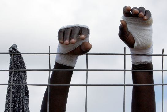 Las manos heridas de un inmigrante se apoyan en la verja de Centro de Estancia Temporal para Inmigrantes (CETI) de Melilla