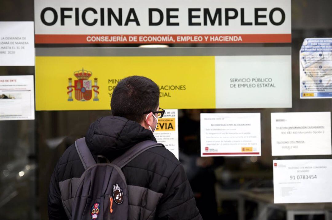 Un joven mira información en una Oficina de Empleo. 