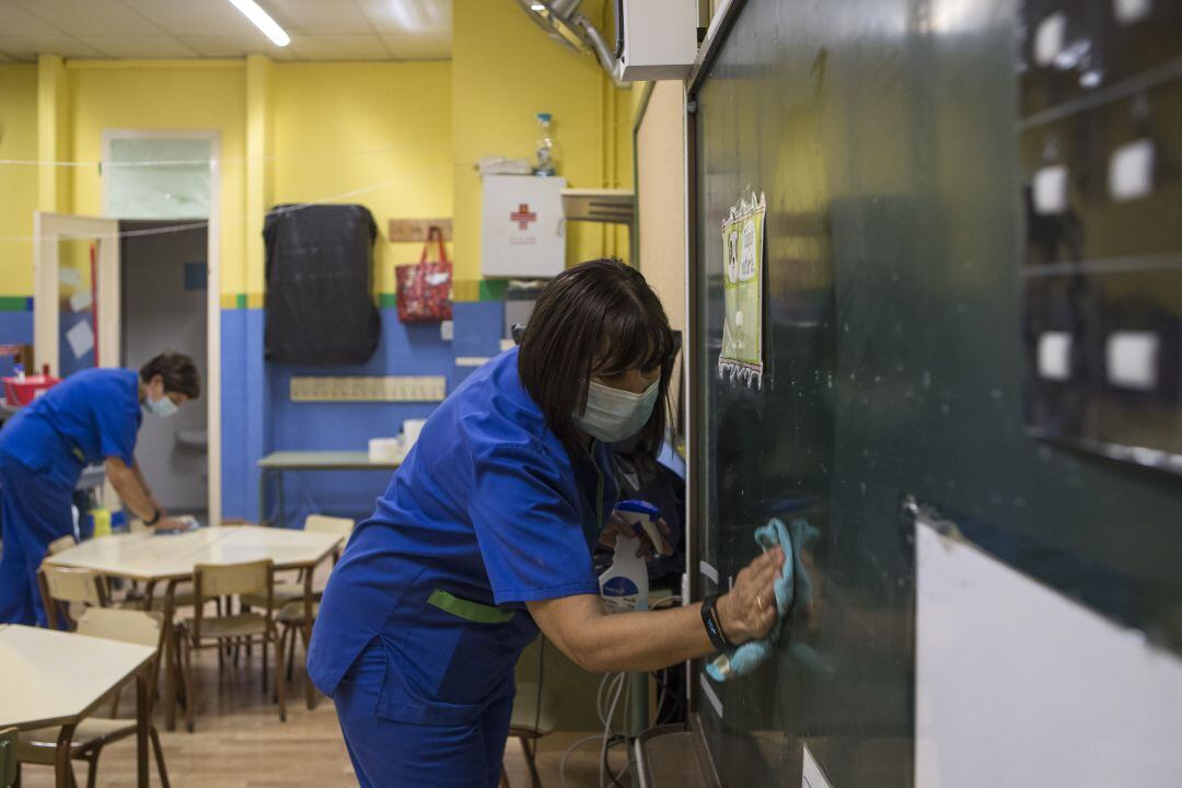 Personal de limpieza desinfectando un aula. 