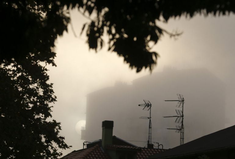 El sol sale envuelto en una densa bruma en una calle de San Sebastián.