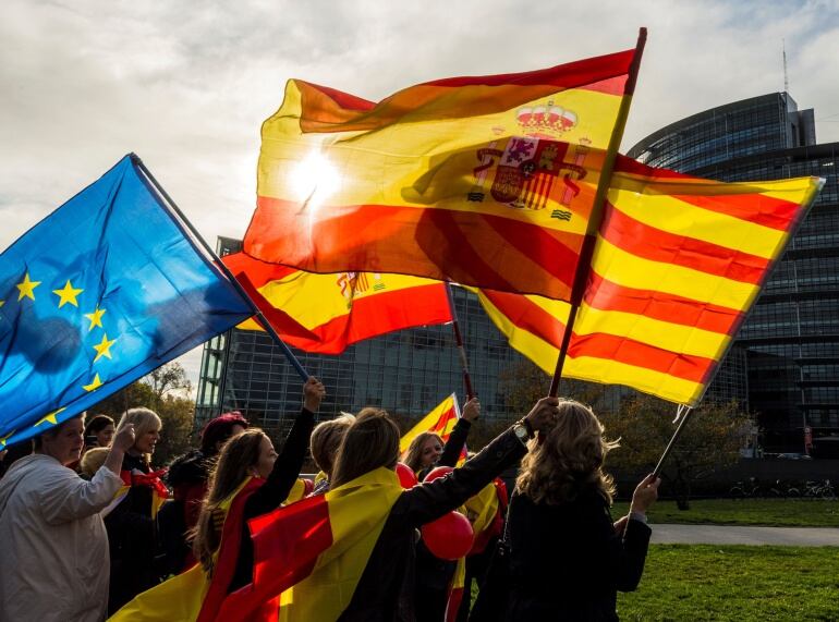 Varios manifestantes con banderas de la Unión Europea, España y Cataluña