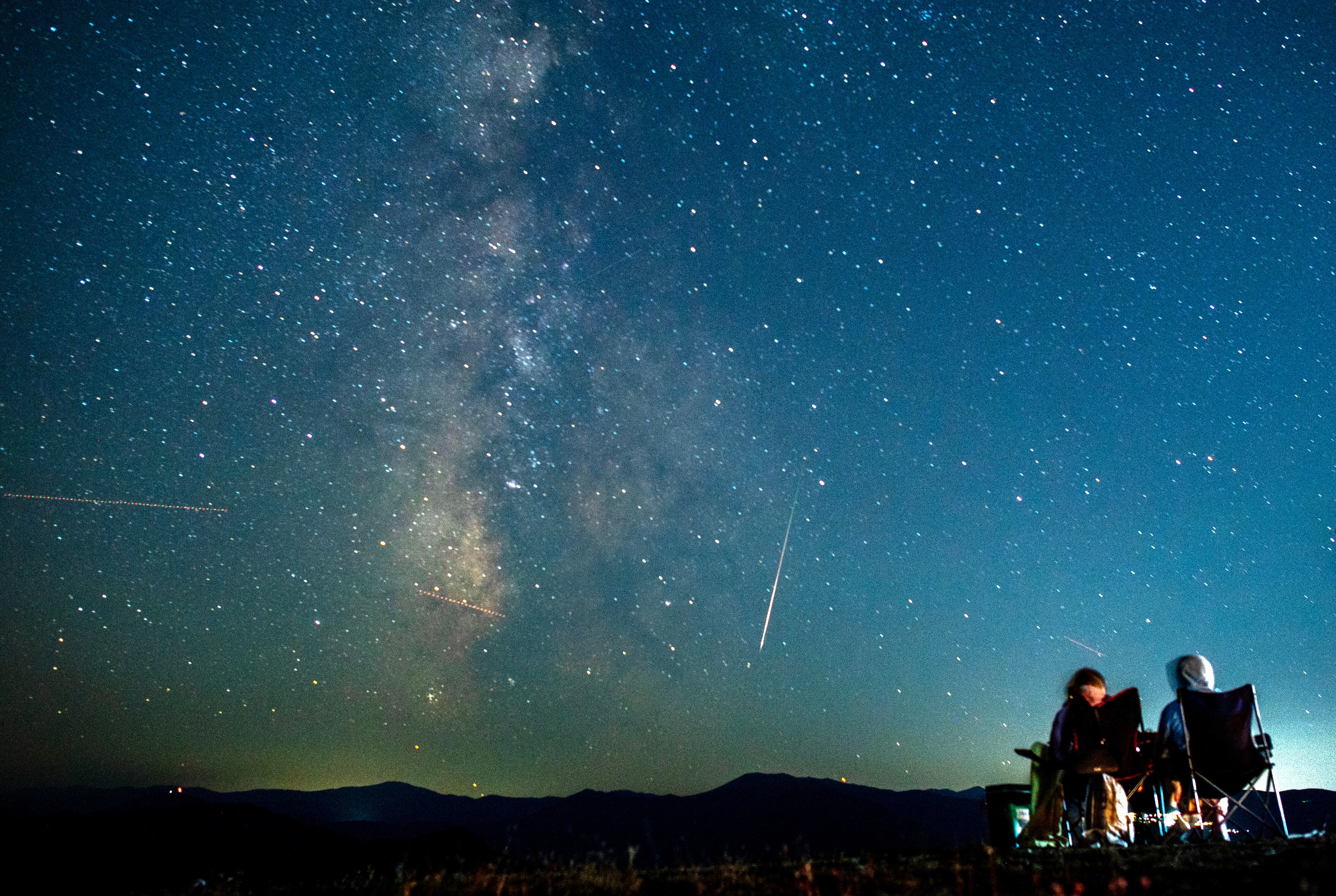 -FOTODELDÍA- EA1048. SKOPJE (REPÚBLICA DE MACEDONIA DEL NORTE), 11/08/2024.- Una pareja observa cómo un meteoro surca el cielo nocturno más allá de la Vía Láctea durante la lluvia de meteoros de las Perseidas sobre el lago Kozjak, a unos 45 km de la capital Skopje (Macedonia del Norte). EFE/EPA/GEORGI LICOVSKI
