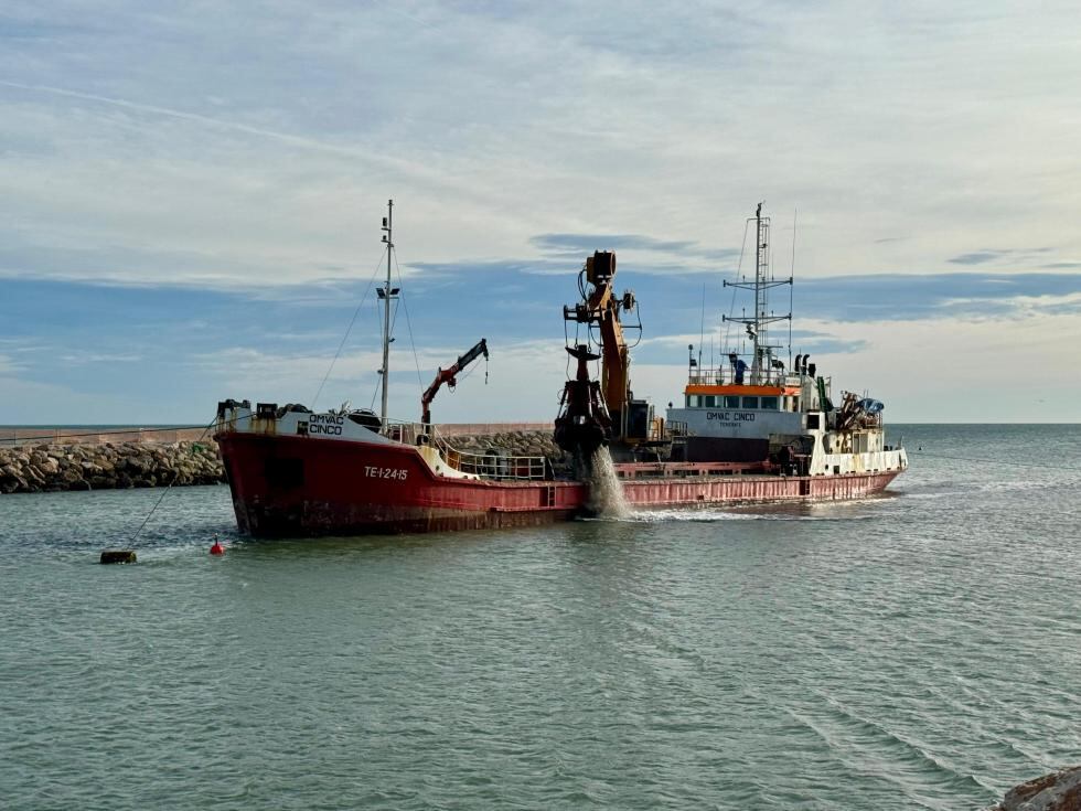 Un barco dragando los sedimentos en la desembocadura del río Xúquer para trasladarlos a la playa de la Goleta, en Tavernes