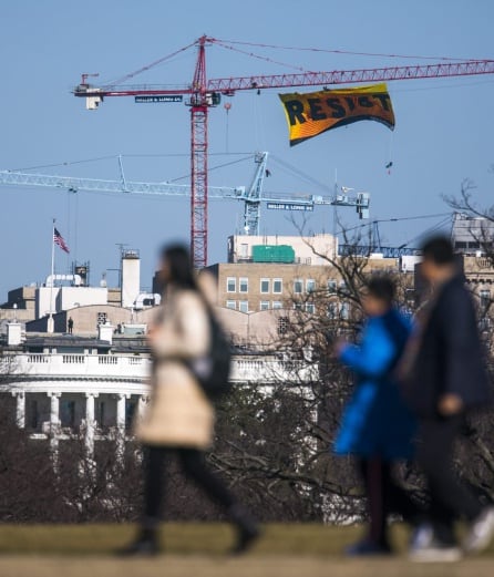 Siete activistas de Greenpeace extienden una bandera con la palabra &quot;Resist&quot; (lit. Resistir) desde una grúa cerca de la Casa Blanca