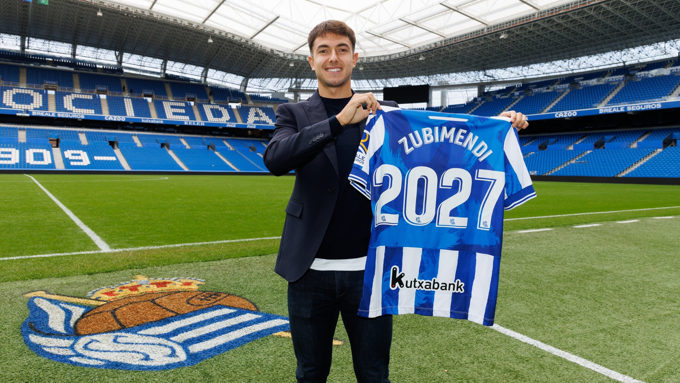 Zubimendi posa con una camiseta y el nuevo año de contrato en la Real