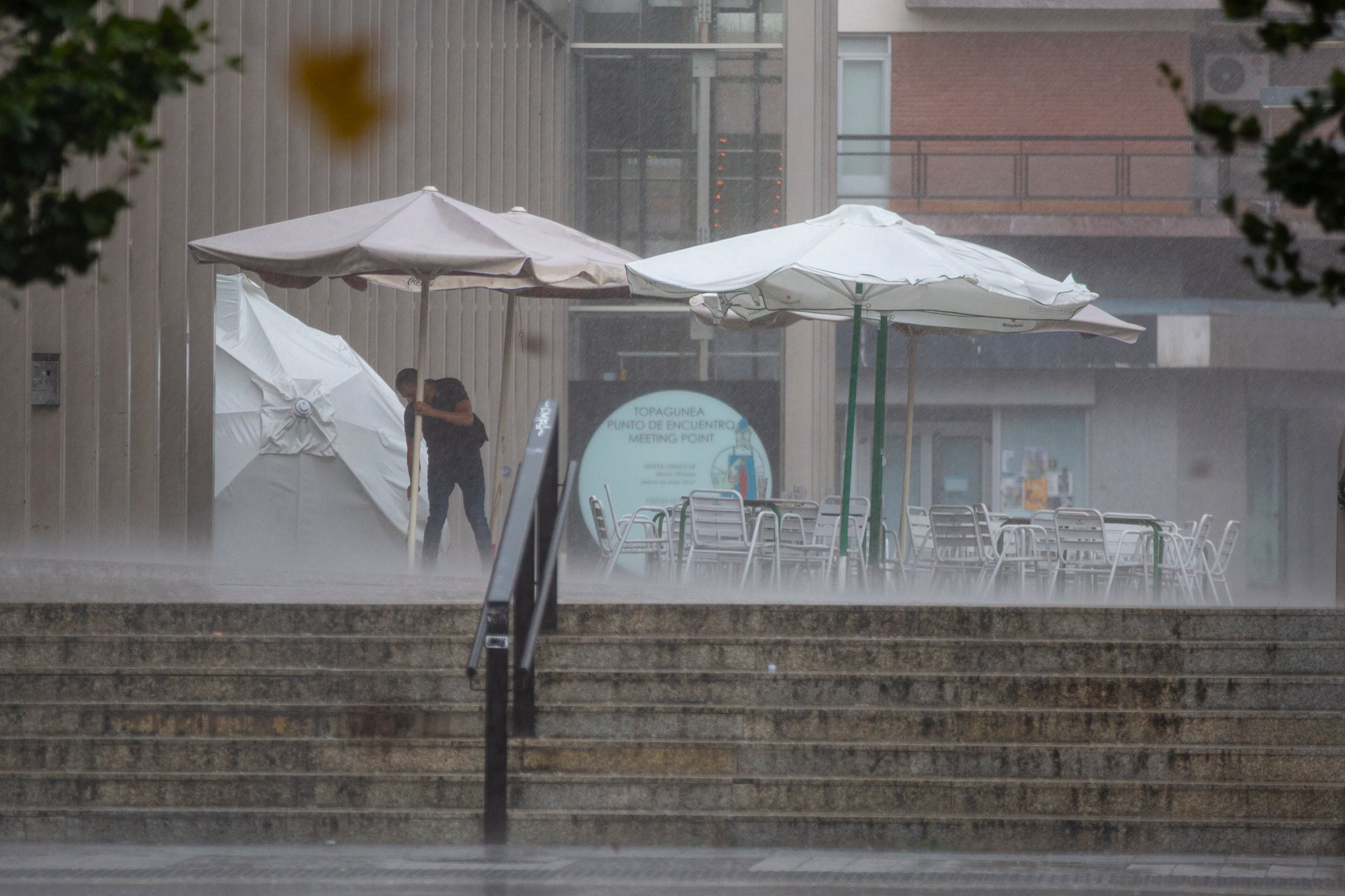 Un camarero retira la terraza de un establecimiento bajo la lluvia, durante una fuerte tormenta que se desató sobre Vitoria