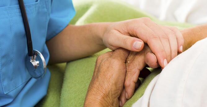 Una paciente con cáncer sujeta la mano de una enfermera en una imagen de recurso