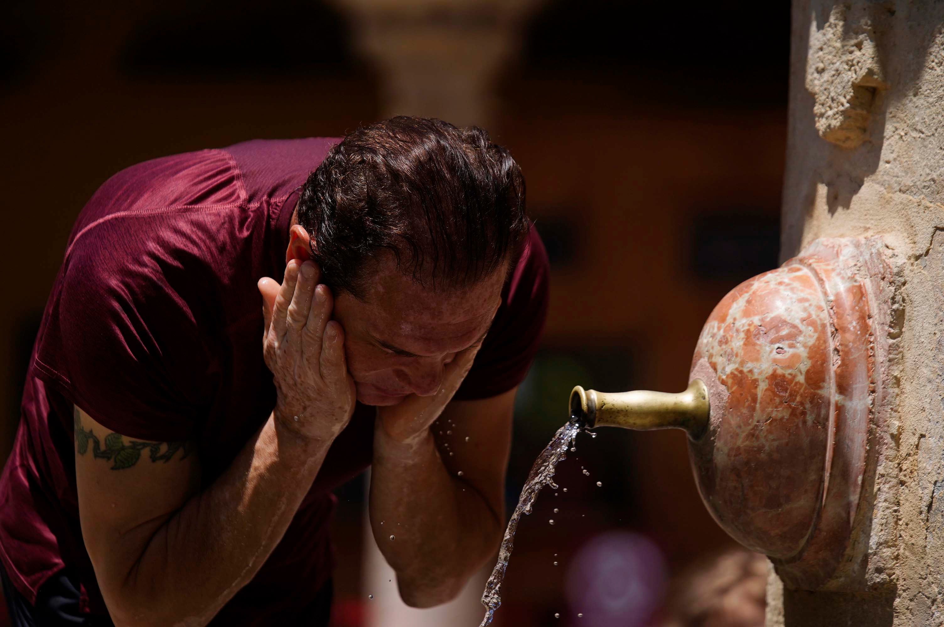 Un turista se refresca en una de las fuentes del Patio de los Naranjos de Córdoba.