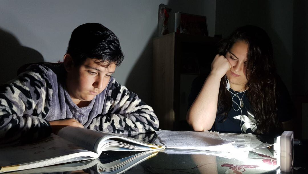 Un niño del barrio almeriense de Las Chancas estudia con la luz de una linterna ante la situación de falta de suministro eléctrico que vive la zona.