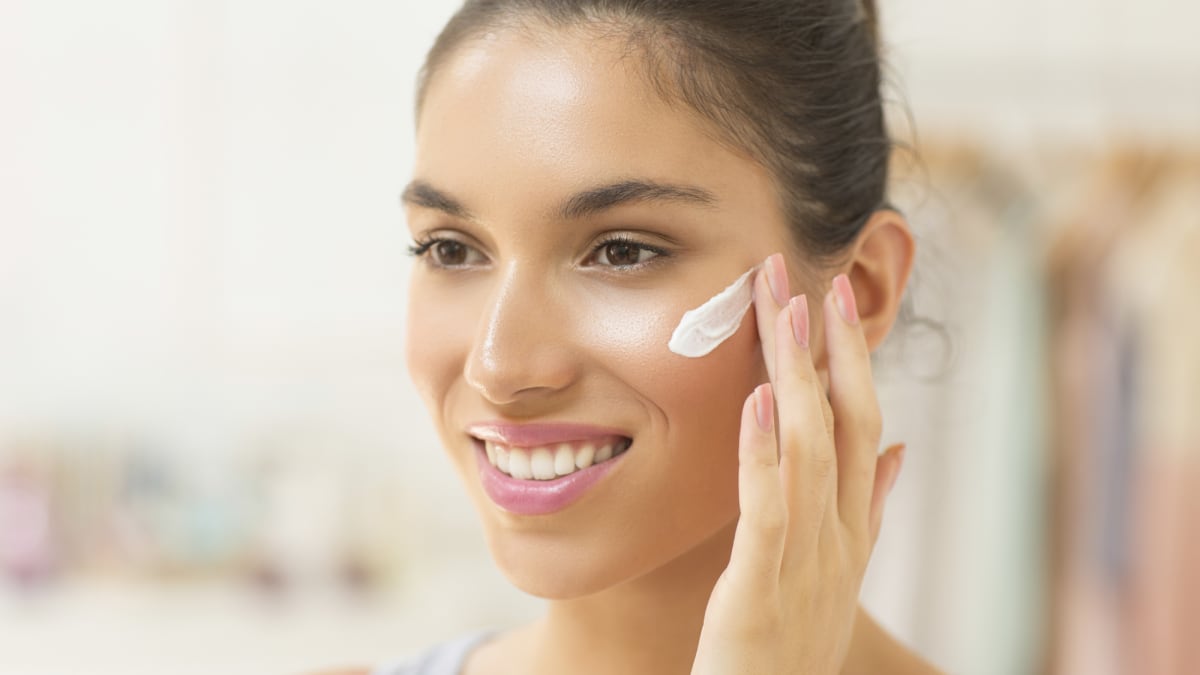 Imagen de archivo de una mujer echándose crema hidratante facial
