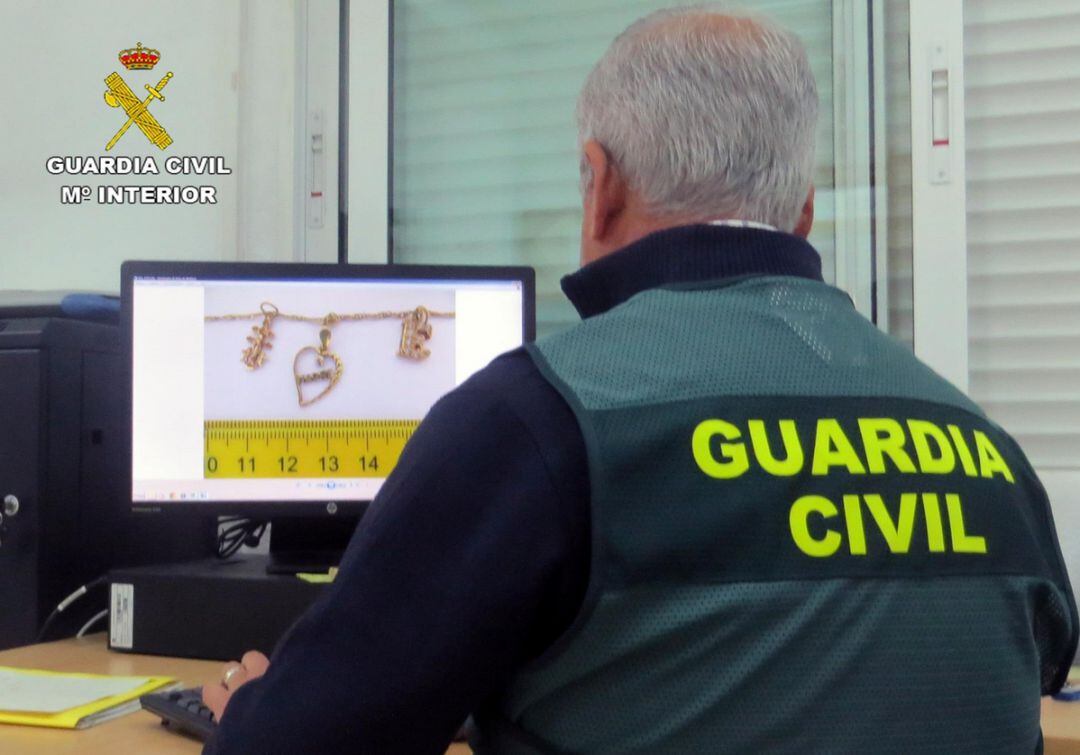 En la imagen un agente de la Guardia Civil observa las pruebas y joyas robadas