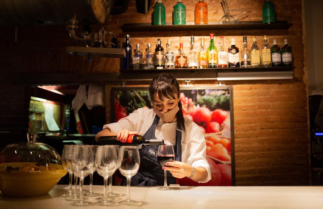 Una camarera sirve una copa de vino en el interior de un bar de Barcelona