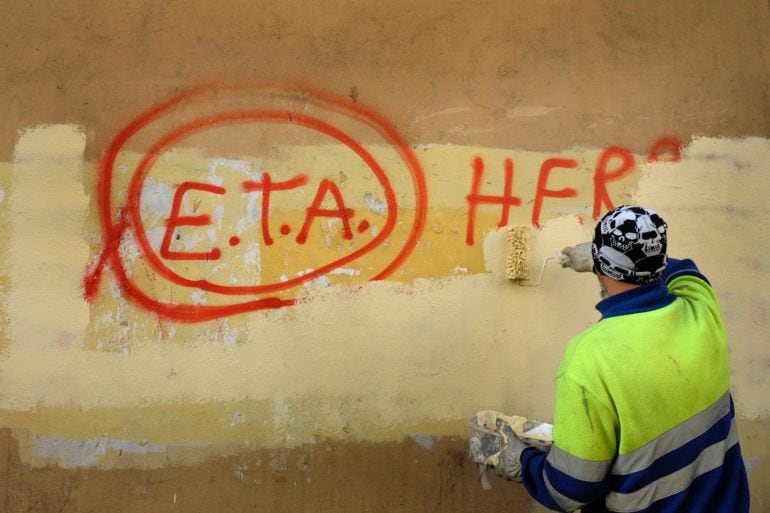 Un operario pinta sobre una pintada de ETA en las calles de Bilbao