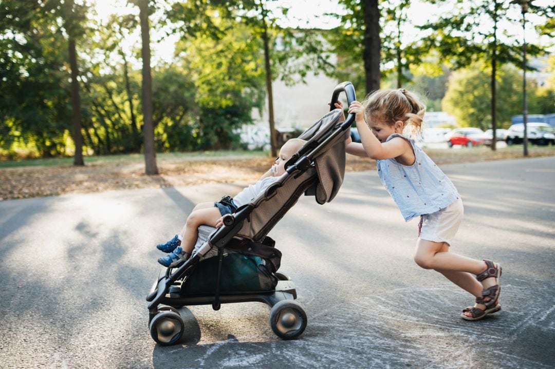 Una niña empuja un carrito de bebé.