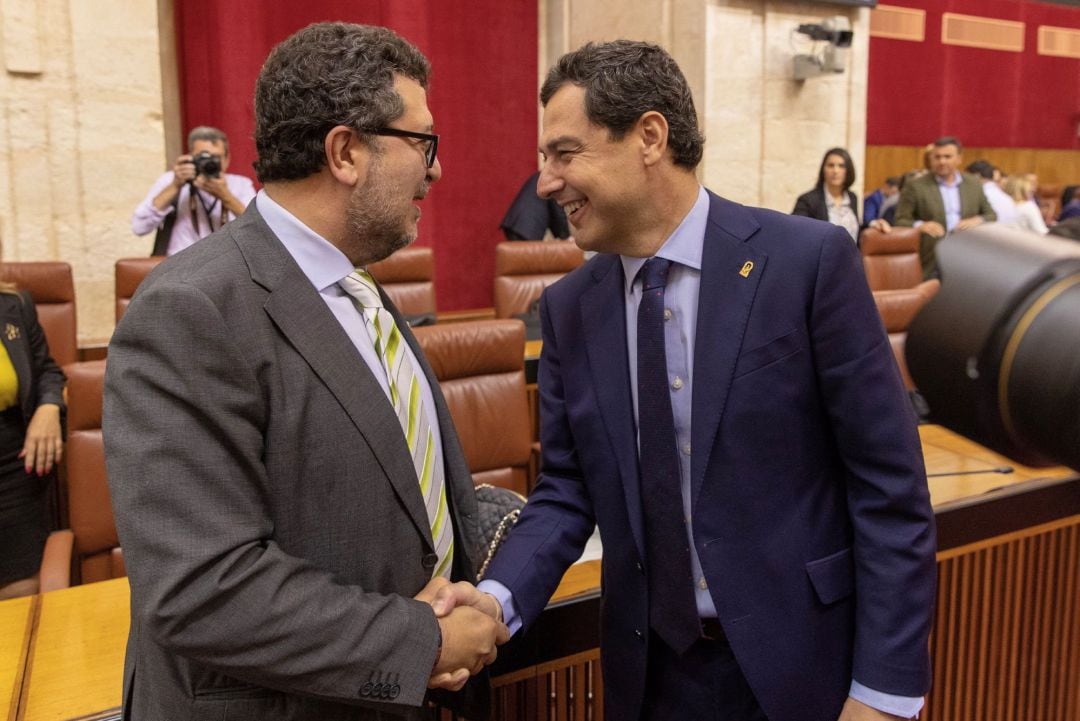 El presidente andaluz, Juanma Moreno, saluda al diputado de Vox, Francisco Serrano, al comienzo del pleno del Parlamento de Andalucía este viernes.