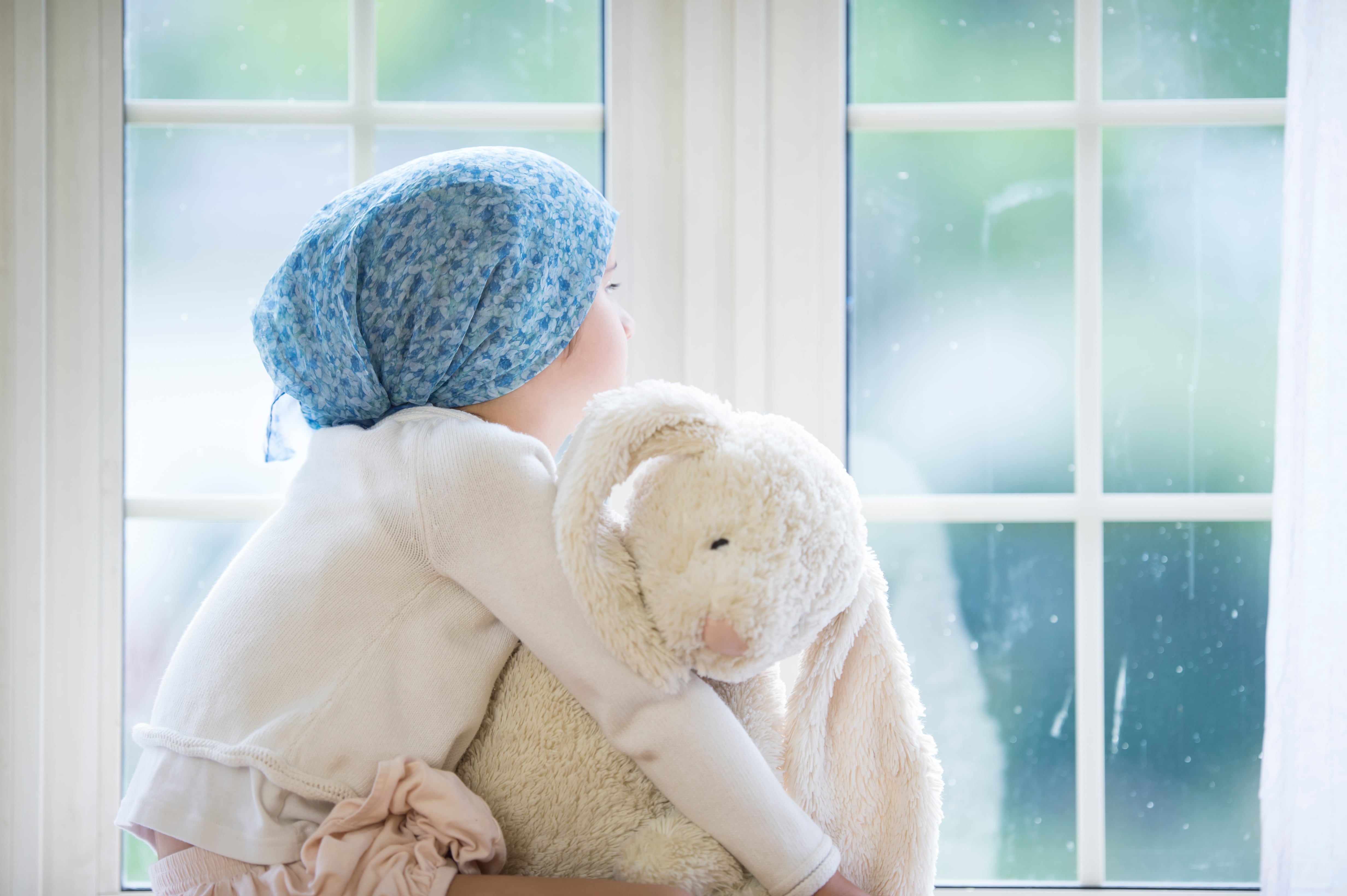 Un niña con cáncer mira por la ventana