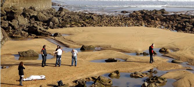 Efectivos de los servicios de emergencia, junto a la camilla con el cuerpo sin vida de la niña de unos 2 años hallada muerta hoy flotando en el mar, en una zona cercana a la costa en Zarautz, después de que su padre hubiera denunciado su desaparición unas horas antes a la Ertzaintza