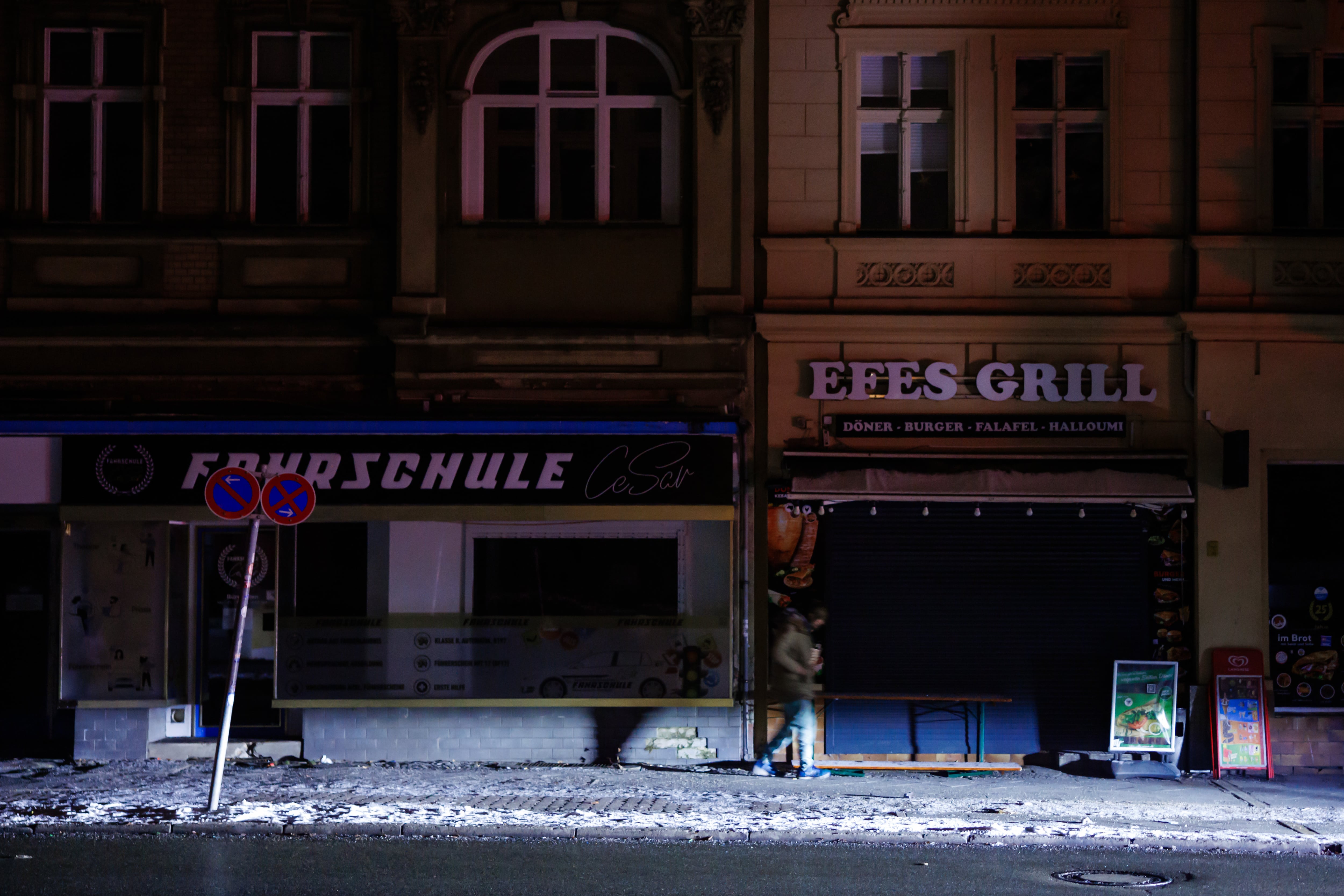 Una persona iluminada por los faros de un coche ante edificios a oscuras durante un apagón en el suroeste de Berlín, Alemania