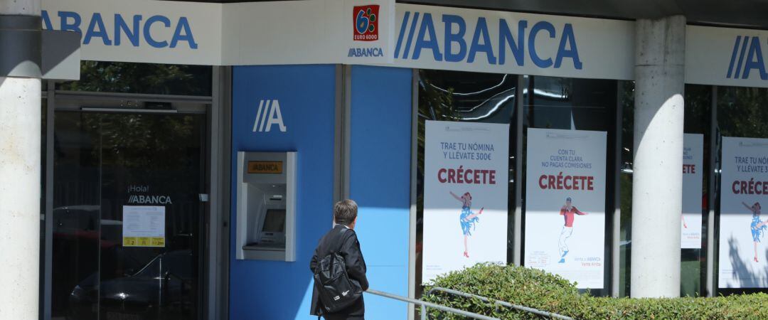 Archivo - Un hombre pasa al lado de una sucursal de Abanca