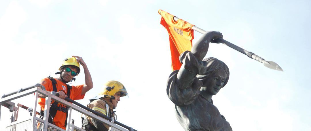 Un trabajador de Alcoa acompañado por un bombero del parque de A Coruña, coloca una camiseta con el lema Cierre no