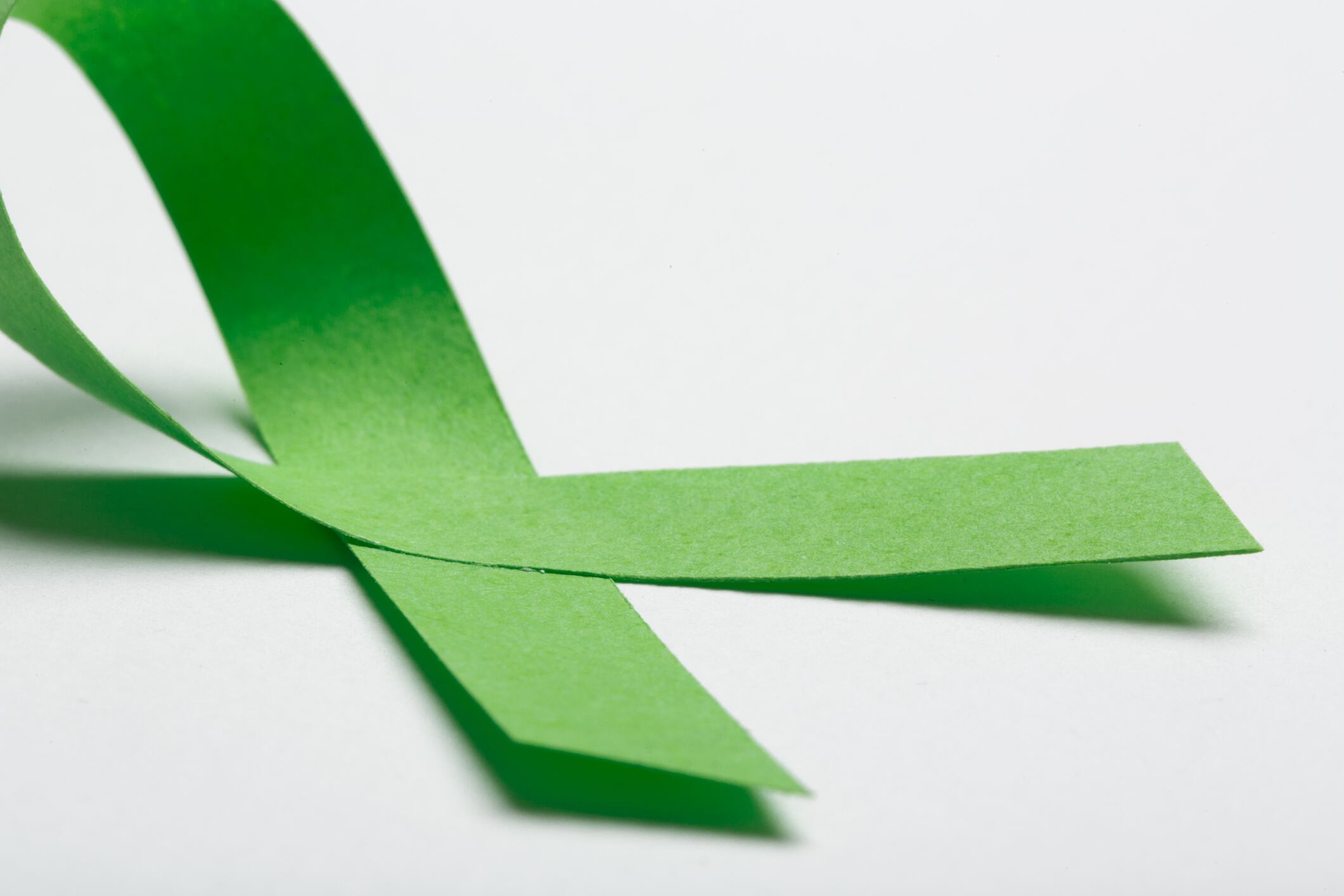 Green handmade awareness paper ribbon on white background.
