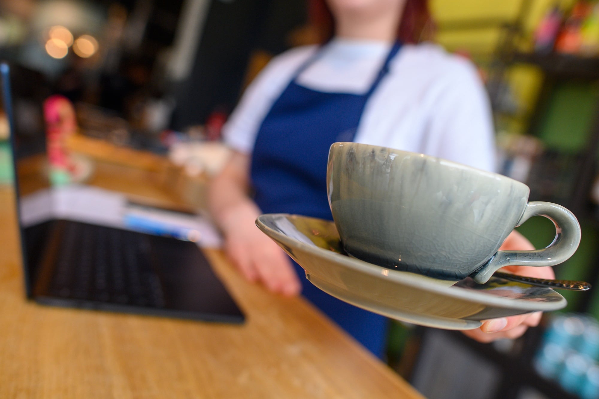 Una camarera ofrece una taza de café.