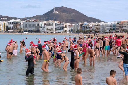 Un centenar de bañistas ataviados como Papá Noel han cruzado hoy desde la orilla de la playa de Las Canteras.