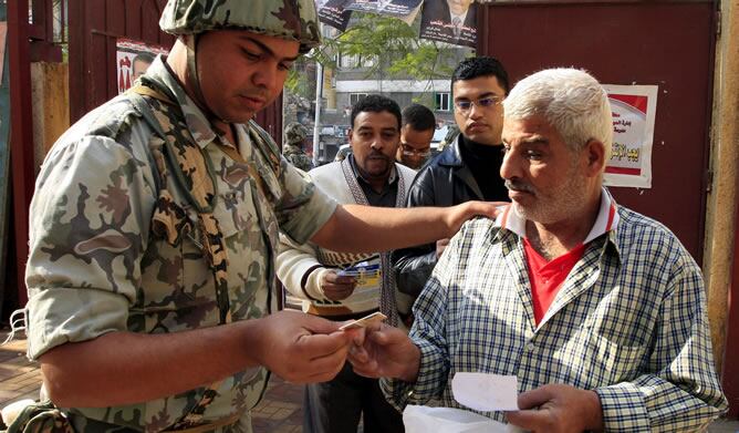 Un soldado egipcio comprueba la documentación de un hombre antes de votar en la primera ronda de las elecciones egipcias