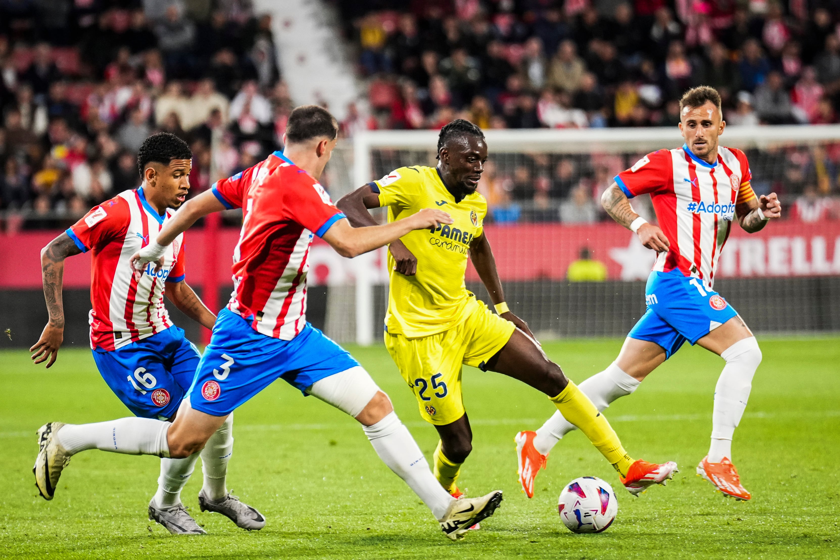 GIRONA, 14/05/2024.- El delantero del Villarreal, Bertrand Traoré, con el balón ante los defensores del Girona durante el encuentro correspondiente a la jornada 36 de Primera División que Girona y Villarreal disputan hoy martes en el estadio de Montilivi, en Girona. EFE / David Borrat.
