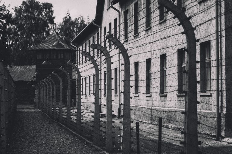 Valla de alambre de púas en Auschwitz Oswiecim, Polonia - 16 de agosto de 2016: Una cerca del alambre de púas y en el fondo una guardia. El sitio es el campamento original (Auschwitz I) del campo de concentración de Auschwitz, ahora el Museo Estatal Ausc