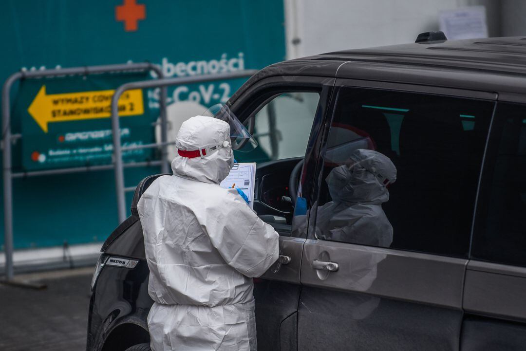 Health workers wear protective suits, masks and gloves as they perform PCR Coronavirus tests in a drive thru point
