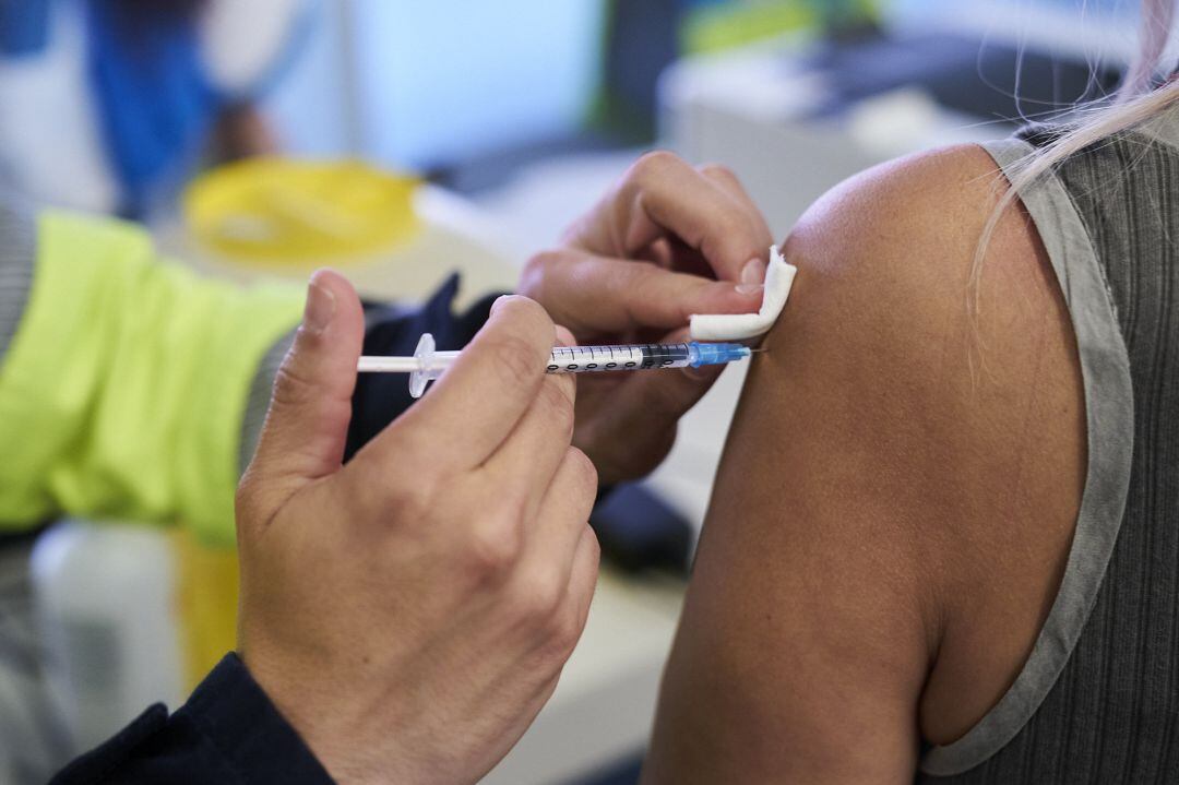 Un sanitario vacuna a una mujer con la dosis de Pfizer 