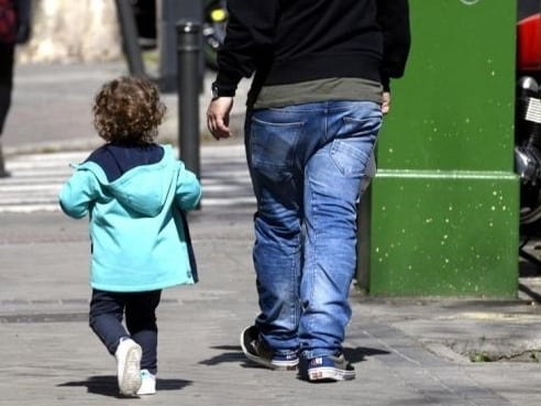 Unos padres pasean junto a su hija por la calle