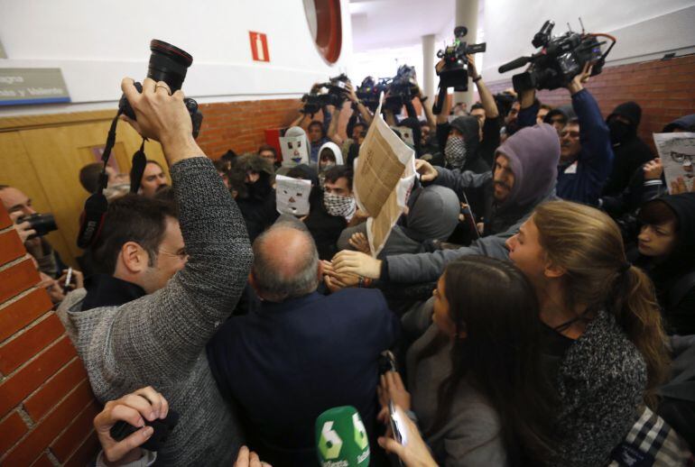 Unos 200 jóvenes, la mayoría con la cara oculta por caretas o pasamontañas, taponan desde dentro la puerta de la facultad de derecho de la Universidad Autónoma de Madrid, para impedir la entrada al expresidente del Gobierno Felipe González, que tenía prev