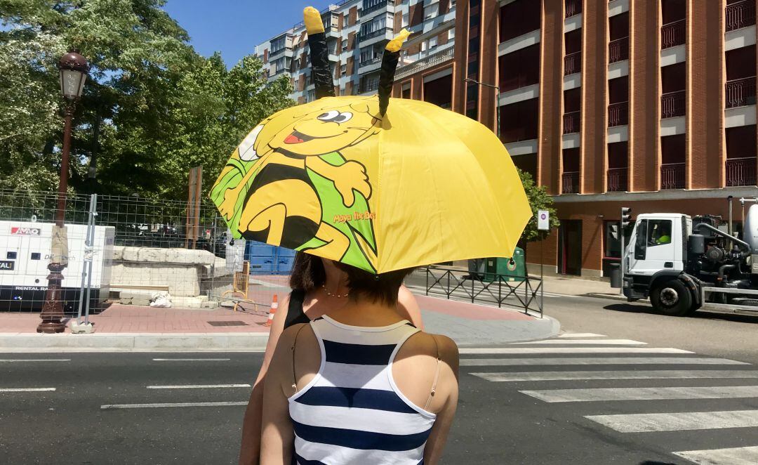 Una mujer se protege de los rayos de sol con un paraguas