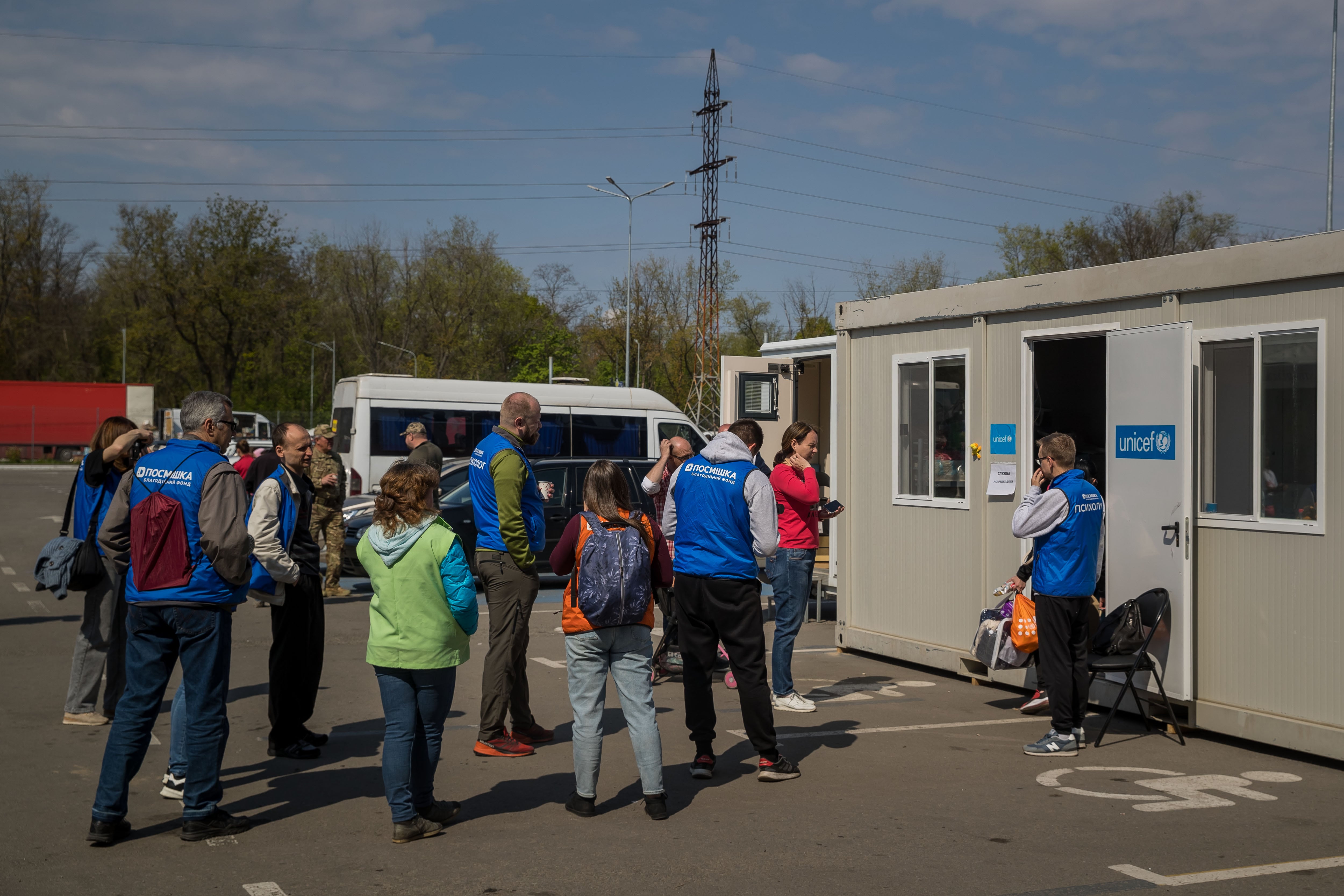 Personal de UNICEF atiende a refugiados en el estacionamiento de un centro comercial, hoy lunes 2 de mayo del 2022 en Zaporiya (Ucrania). La ciudad de Zaporiya, a unos 220 kilómetros de Mariúpol, espera la llegada del convoy con los primeros civiles que permanecían dos meses escondidos en la acería de Azovstal, con técnicos municipales, médicos y organizaciones humanitarias preparados para atenderlos.